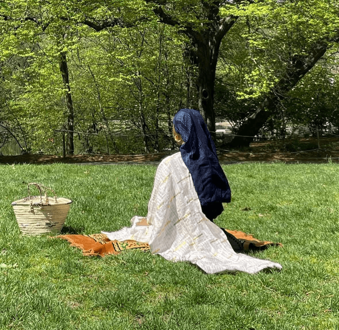 Mariam in a white dress holding a woven basket among flowers