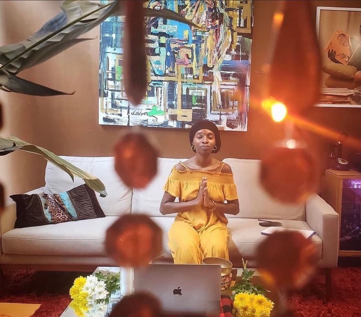 Mariam meditating in stillness, hands in prayer, warm light through beaded curtain