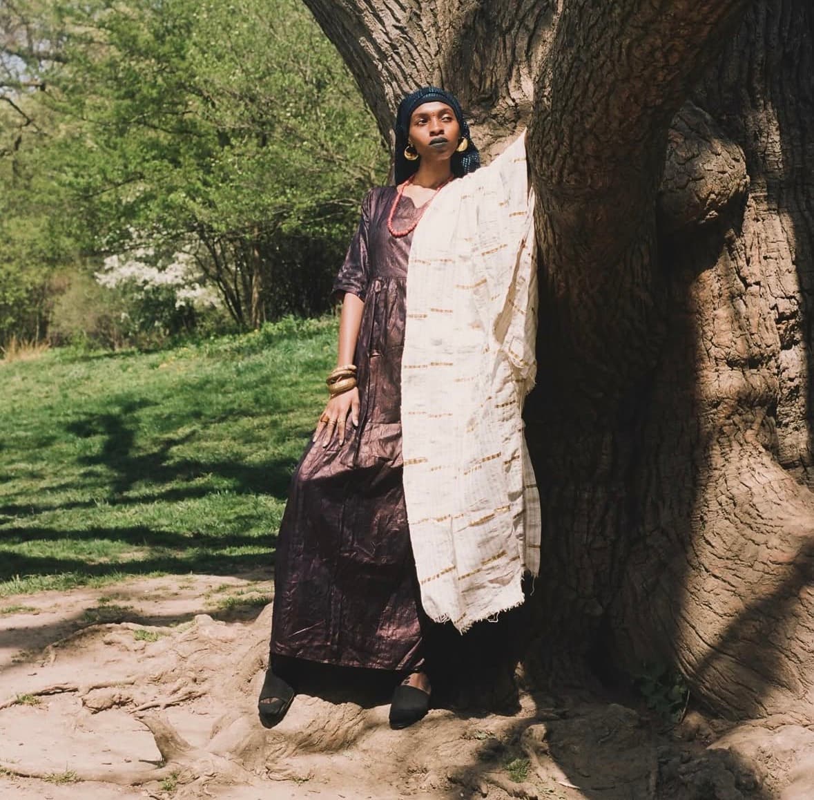 Mariam Kouyate standing against an ancient tree in traditional Mandingue dress